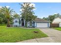 Inviting one-story home with a two-car garage, a blue exterior, mature trees, and manicured landscaping at 28707 Raleigh Pl, Wesley Chapel, FL 33545