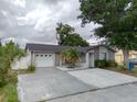 Charming single-story home featuring a gray exterior, well-maintained lawn, mature landscaping, and a two car garage at 9516 Woodborough Ct, Tampa, FL 33615