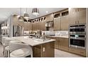 Elegant kitchen featuring modern appliances, stylish lighting, a center island with seating, and sleek cabinetry at 14375 Hammock Oak St, Parrish, FL 34219