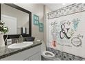 Cozy bathroom featuring a vanity, toilet, patterned shower curtain, and tasteful decor, offering functionality and style at 4704 Wild Senna Blvd, Tampa, FL 33619