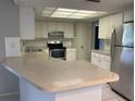 Bright kitchen with stainless steel appliances, white cabinets, and spacious breakfast bar at 7240 Rosarian Dr, Port Richey, FL 34668