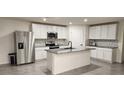 Modern kitchen boasts white cabinets, stainless steel appliances, and a granite-topped island at 16650 Windmill Forge Pass, Wimauma, FL 33598