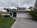 Front exterior featuring a concrete driveway, a two-car garage, and mature trees around the house at 13382 Drummond Ave, Port Charlotte, FL 33953