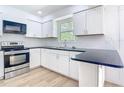Modern kitchen featuring white cabinets, black countertops, and stainless steel appliances at 7341 Hart St, Englewood, FL 34224