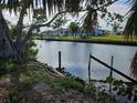 View of waterfront property featuring a canal with dock pilings and lush landscaping at 801 Marlin Dr, Punta Gorda, FL 33950