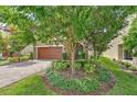 Home exterior featuring lush front lawn with mature trees and a brick driveway at 12990 Burns Dr, Odessa, FL 33556