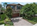 Two story home showcasing a beautiful front exterior with a brick driveway and well maintained landscaping at 12990 Burns Dr, Odessa, FL 33556