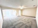 Large living room featuring neutral carpeting, abundant natural light, and a ceiling fan for added comfort at 4605 Ashburn Square Dr, Tampa, FL 33610