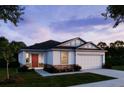 Charming single-story home showcasing stone accents, neutral paint, a red front door, manicured lawn and a two-car garage at 12518 Maginn Ct, Weeki Wachee, FL 34614