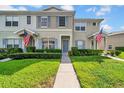 Inviting exterior of a townhome featuring a walkway, green lawn, and American flag at 5857 Fishhawk Ridge Dr, Lithia, FL 33547