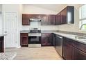 Modern kitchen with dark brown cabinets, granite countertops, and stainless steel appliances at 12128 Grouse Ave, Port Charlotte, FL 33981