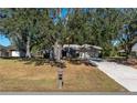 House exterior showcasing a driveway, lawn, and large shade trees at 15123 Copeland Way, Spring Hill, FL 34604