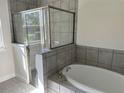 Modern bathroom featuring a soaking tub, tiled walls, and a glass-enclosed shower at 1449 Marjorie Ln, North Port, FL 34286