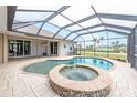 Relaxing enclosed pool area with a spa and views of the manicured lawn at 8305 Welsford Rd, Port Charlotte, FL 33981