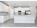 Modern kitchen featuring white cabinets, stainless steel appliances, and an island with granite countertops at 2576 Pecan St, North Port, FL 34287