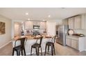 Modern kitchen featuring a granite-topped island with seating, stainless steel appliances, and light-gray cabinets at 5064 Roble Ave, Spring Hill, FL 34606