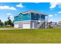 Stylish two-story waterfront home featuring a bright blue exterior, ample garage space, and lush green lawn at 6771 Seaview Blvd, Hudson, FL 34667