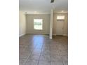 Open-concept living room with tiled floor, natural light from a large window and white trim at 1608 Alliance Ave, North Port, FL 34286
