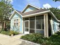 Light blue home with cream trim, a screened porch, and small decorative front garden at 6212 Abbott Station Dr, Zephyrhills, FL 33542