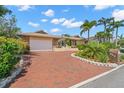 Beautiful home featuring a brick driveway and lush landscaping, providing an inviting and well-maintained exterior at 852 3Rd Ave S, Tierra Verde, FL 33715