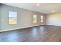 A bright living room with gray wood floors and three large windows offering natural light at 2223 Hattie Ct, North Port, FL 34288