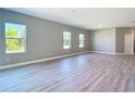 Spacious living area with wood-look flooring, neutral paint, and ample natural light from three large windows at 2423 Sadnet Ln, North Port, FL 34286