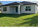 Rear exterior view of a home with a covered patio and lush green lawn at 2370 Allsup Ter, North Port, FL 34286