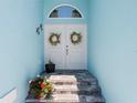 Inviting front entrance featuring double doors, stone steps, and colorful flower arrangements at 10391 Coquina Ct, Placida, FL 33946
