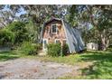 Charming A-frame home with a metal roof, nestled among mature trees and landscaping at 8309 Oakgren Rd, Brooksville, FL 34601
