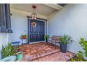 Inviting front porch with a brick floor, a wreath on the door, and a cozy seating area at 205 Bengal Cir, Oldsmar, FL 34677
