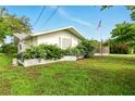 A verdant lawn highlights this cozy white home, accented by flowering bushes and a flagpole displaying the American flag at 5728 Colonial Dr, New Port Richey, FL 34653