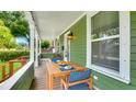 Inviting front porch with wood floors, decorated table, seating, and green exterior siding at 2715 14Th N Ave, St Petersburg, FL 33713
