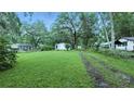 Exterior view of home situated on a expansive grassy lot with mature trees and a long driveway at 242 Zoller St, Brooksville, FL 34601