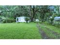 A quaint home surrounded by a lush lawn and trees, featuring a driveway leading to the backyard at 242 Zoller St, Brooksville, FL 34601