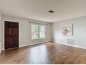 Inviting living room featuring a front door, large window, and beautiful wood-look tile flooring at 7318 Tranquil Dr, Spring Hill, FL 34606