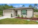 Attractive single-story home showcasing a well-maintained lawn, flower beds, and a two-car garage at 14025 Canyon Swallow Rd, Weeki Wachee, FL 34614