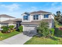 Two-story house with a neutral color scheme, a two-car garage, and a landscaped yard at 10662 Hawks Landing Dr, Land O Lakes, FL 34638