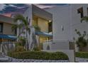 Exterior of a tan condo building with lush landscaping and a well-maintained facade at 722 Pinellas Bayway S # 102, St Petersburg, FL 33715