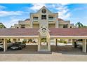 Exterior view of a condo building featuring covered parking, mature landscaping, and a well-maintained facade at 722 Pinellas Bayway S # 102, St Petersburg, FL 33715