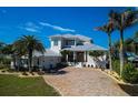 Beautiful two-story home with a gray metal roof, paver driveway, and meticulously landscaped grounds at 764 S Mccall Rd, Englewood, FL 34223