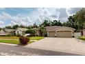 Traditional home with a 3-car garage, an American flag, a brick driveway, and a well-maintained lawn at 4506 Gentrice Dr, Valrico, FL 33596