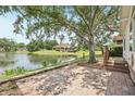 Lakeside backyard with a brick patio, mature trees, and a peaceful view overlooking the water at 6621 La Mesa Rd, Land O Lakes, FL 34637