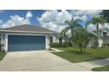 Well-maintained home with a blue garage door, palm trees, and a manicured lawn at 13443 Graham Yarden Dr, Riverview, FL 33579