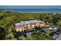 Coastal condo building with balconies, mature landscaping, and covered parking near the water at 23465 Harborview Rd # 223, Punta Gorda, FL 33980