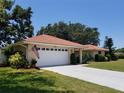 Charming single-story home with a terracotta tile roof, lush landscaping, and an attached two-car garage at 1608 Bob O Link Dr, Venice, FL 34293