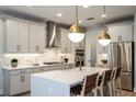 Bright kitchen features an island, stainless steel appliances, stylish pendant lights, and gray cabinets at 240 Vistera Blvd, North Venice, FL 34275