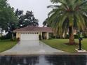 Single-story home with a red tile roof, white garage door, and a palm tree at 1608 Bob O Link Dr, Venice, FL 34293