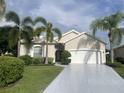 Tan single story house with white garage door and palm trees at 750 Pond Lily Way, Venice, FL 34293