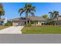 Well-maintained single-story home with a two-car garage, long driveway, and a green lawn at 1336 Roosevelt Dr, Venice, FL 34293