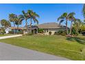 Charming single-story home featuring lush landscaping and mature palm trees in a well-maintained front yard at 1336 Roosevelt Dr, Venice, FL 34293